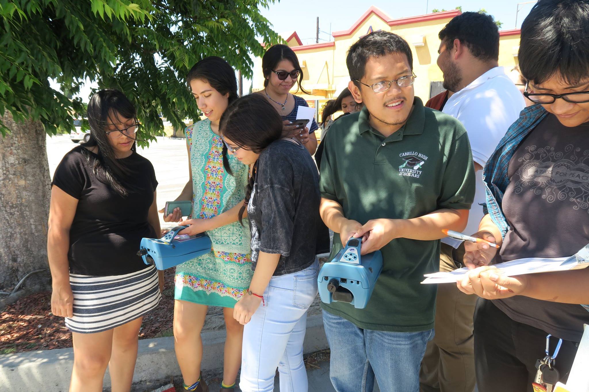 A group of youth, one is holding a machine to test air quality